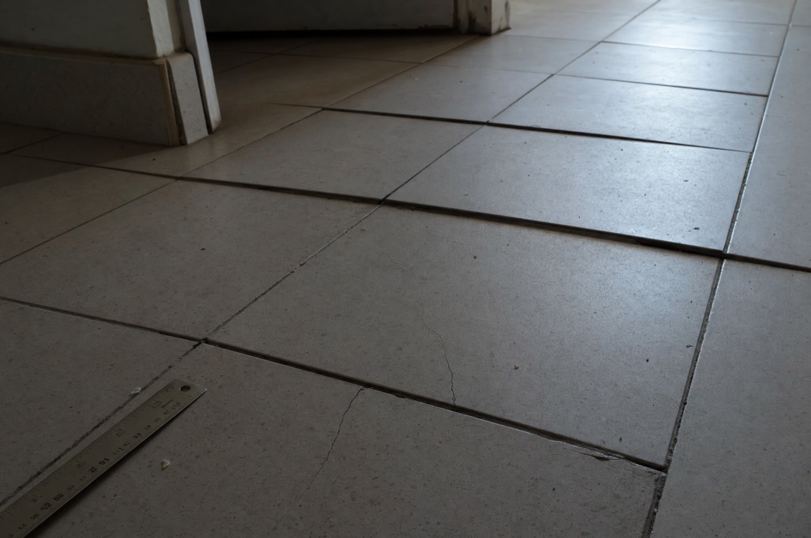 A poorly installed tile floor with cracked grout and uneven lippage
