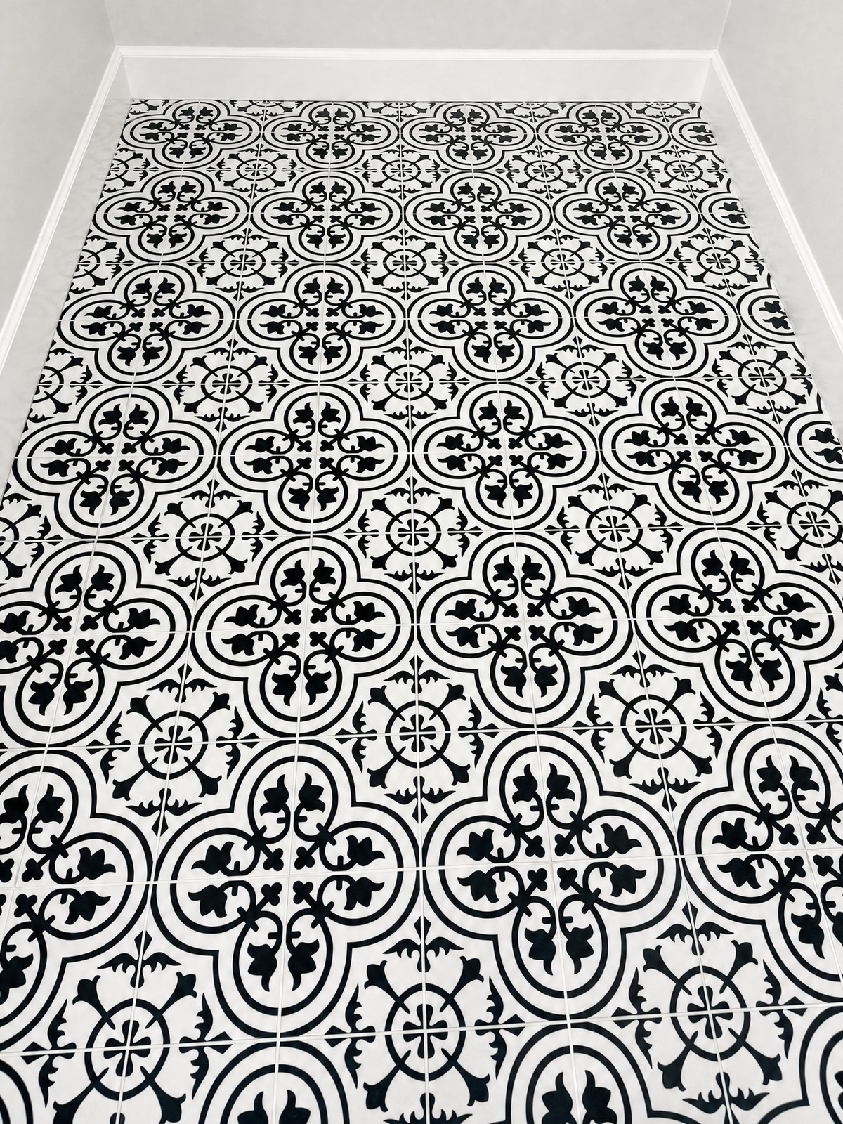 Black and white patterned encaustic-look tile bathroom floor laid tight to the walls