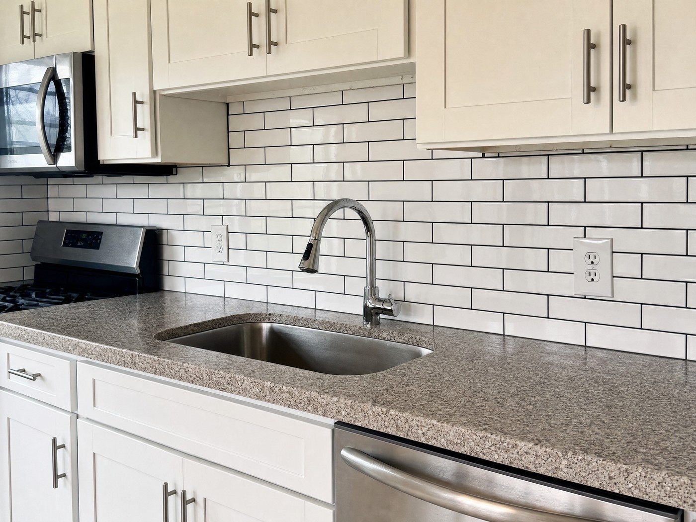 Classic white subway tile backsplash with dark charcoal grout run full height between counter and cabinets